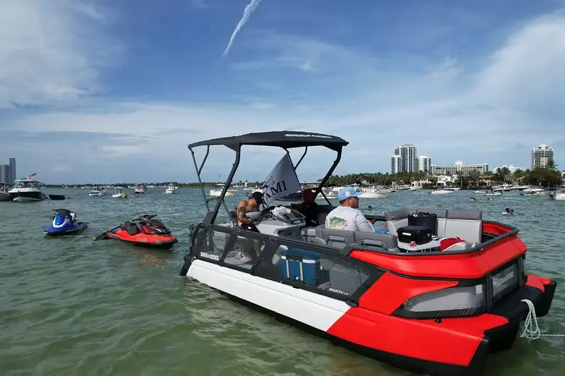 Canopy-top pontoon boat with jet skis at the Haulover sandbar